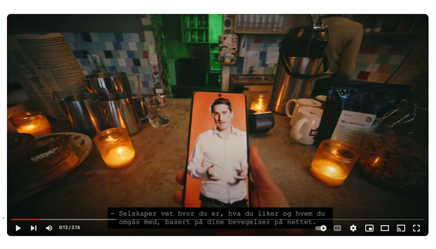 Skjermdump fra filmen "Hvor lang er den digitale halen din?". På skjermen ser vi en telefon med en video med Finn Myrstad fra Forbrukerrådet. I bagfunnen ser vi en bardisk.